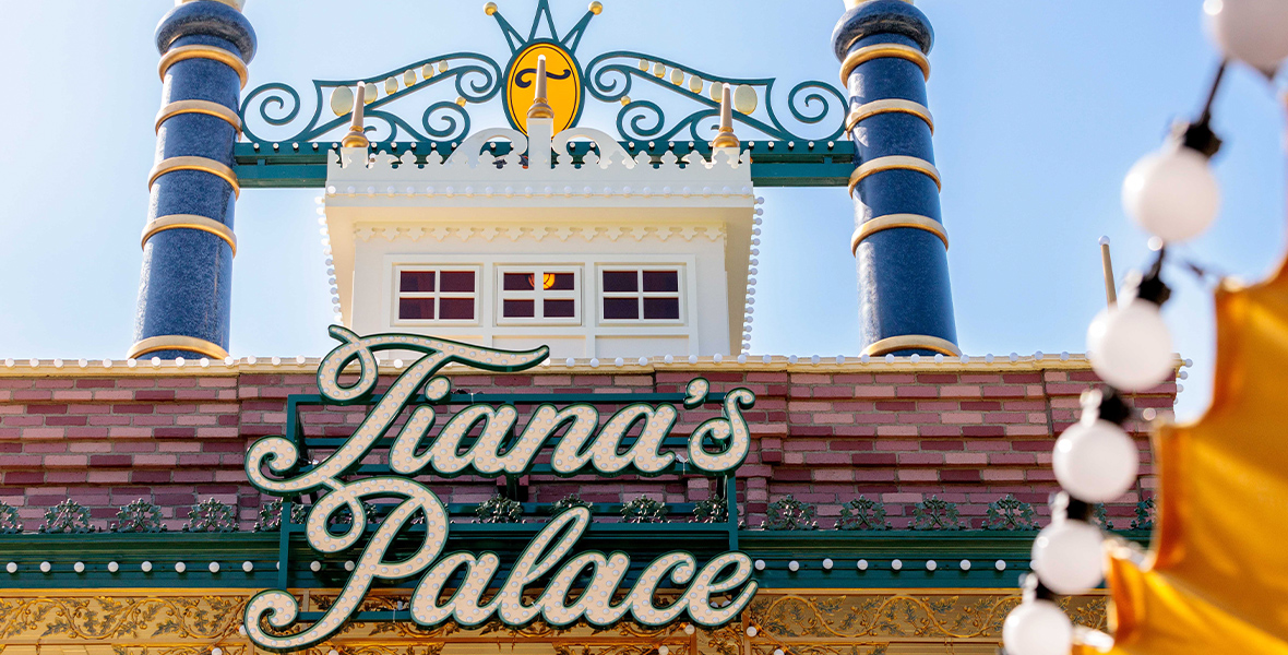 The Tiana’s Palace sign at Disneyland Park is framed by a full-scale representation of the captain’s cockpit and two smokestacks as if from a Mississippi riverboat.