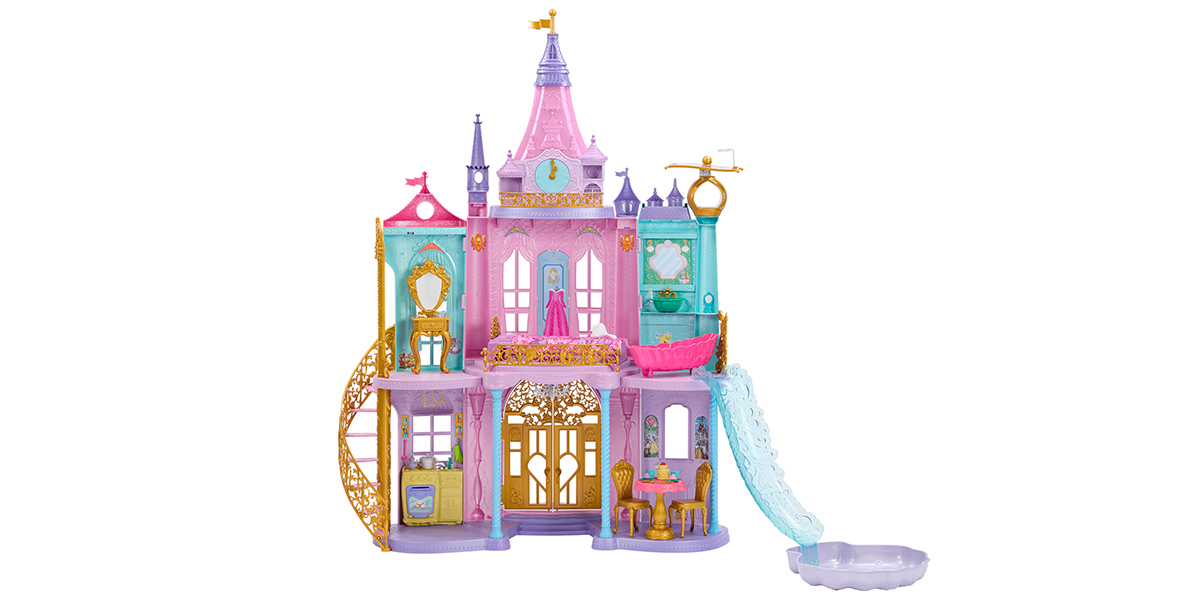 A toy Disney Princess Castle. The top floor features a vanity, Aurora’s pink dress on a dress stand, and a pink bathtub. The bathroom with the tub also features a waterslide that leads to a pool on the ground floor. The ground floor features a kitchen, gold entry doors, and a dining room. 