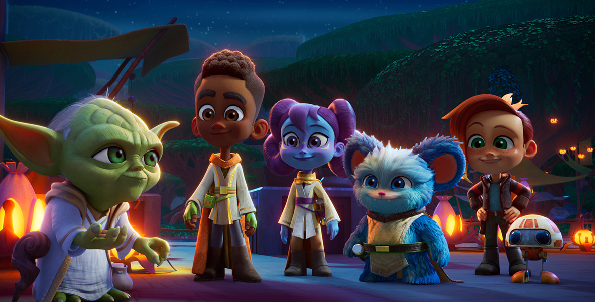 In an image from Lucasfilm’s Star Wars: Young Jedi Adventures, Master Yoda (voiced by Piotr Michael) with Jedi Younglings, Kai Brightstar (voiced by Jamaal Avery Jr.), Lys Solay (voiced by Juliet Donenfeld) and Nubs (voiced by Dee Bradley Baker) and their friends Nash Durango (voiced by Emma Berman), and RJ-83 (voiced by Jonathan Lipow) are seen standing together on the planet Tenoo. It is nighttime, and lit-up dwellings can be seen behind them. Hills can be seen in the distance.