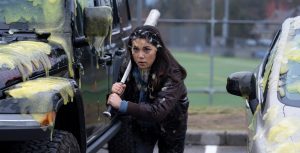 In the Goosebumps episode "Cuckoo Clock of Doom," actor Ana Yi Puig holds a baseball bat and crouches between two cars. Puig and the cars are covered in green goo.