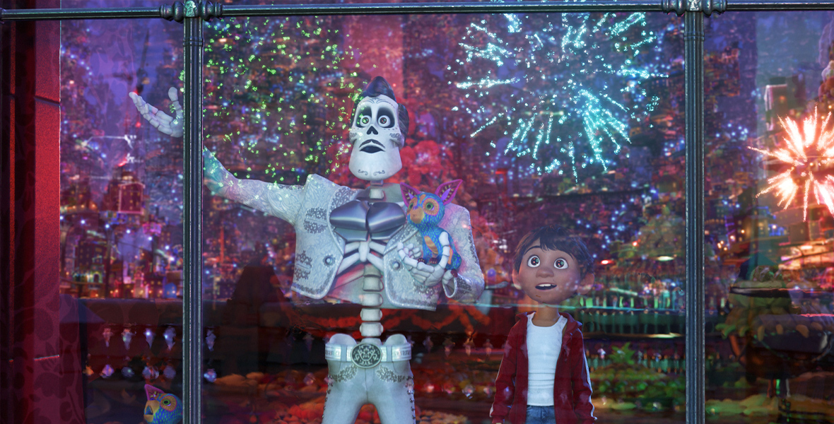 In an image from Disney and Pixar’s Coco, Ernesto de la Cruz (voiced by Benjamin Bratt), left, is showing Miguel (voiced by Anthony Gonzalez), right, a skyline full of fireworks through the window of a building. Ernesto is holding an alebrijes in his hand.