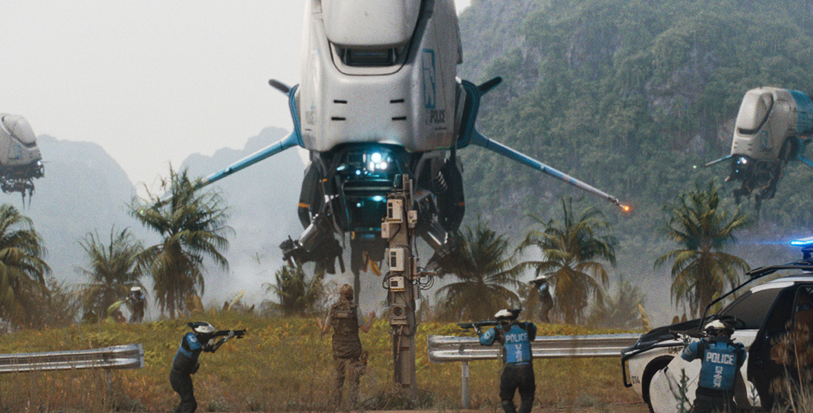 In a jungle, a trio of futuristic-looking police helicopters overhead and a trio of police officers on foot surround Colonel Howell, played by Allison Janney, in The Creator.