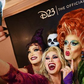 Performers dressed as the villainous Sanderson Sisters pose for a selfie.