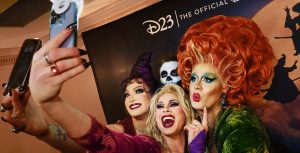 Performers dressed as the villainous Sanderson Sisters pose for a selfie.