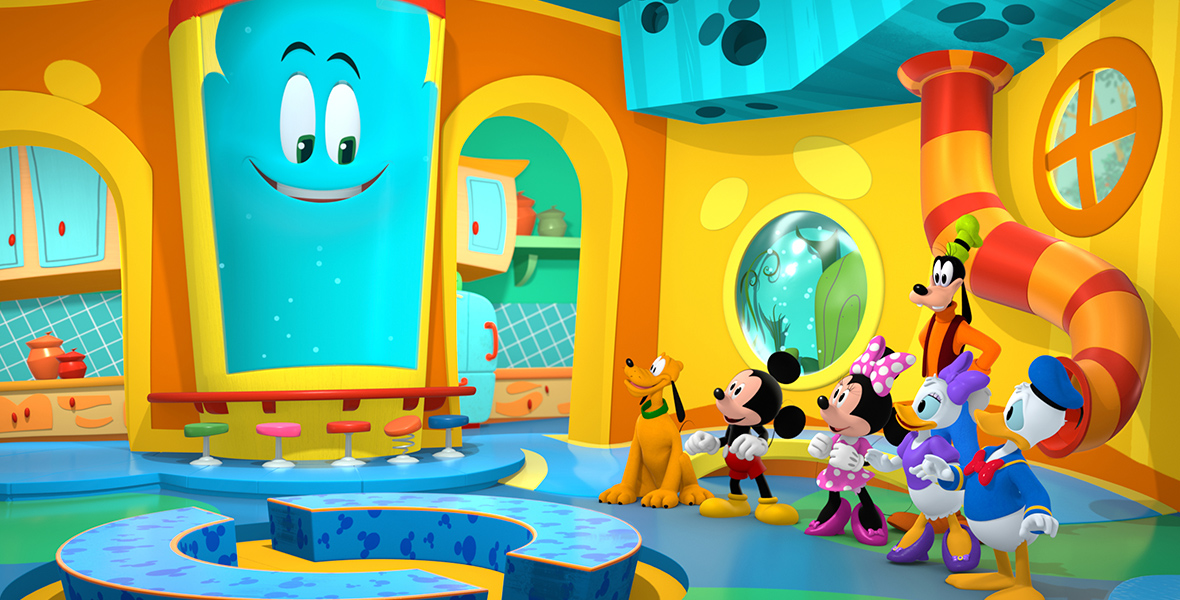 In an image from Disney Branded Television’s Mickey Mouse Funhouse, Funny (voiced by Harvey Guillén) is seen with Mickey Mouse (voiced by Bret Iwan) and the gang inside a colorful kitchen of sorts. There is a counter with stools, cabinets, and several other benches to sit on.