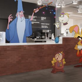 In a scene from the short film Once Upon a Studio, Moana holds Flounder. Merlin stands behind the counter at The Snuggly Duckling café and waves his magic wand. Chip and Mrs. Potts are airlifted above the counter. Cogsworth, March Hare, and the Mad Hatter are standing in front of the counter. Lucille Krunklehorn is on the other side of the counter.
