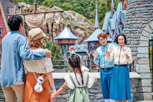Two Cast Members greet three guests outside the gates of World of Frozen.