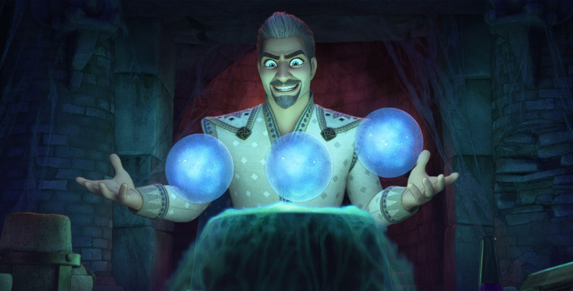 In this still image from Walt Disney Feature Animation’s Wish, King Magnifico stands behind a bubbling caldron, his arms out to either side, apparently using magic to make three glowing blue orbs hover above the caldron. The green glow from the caldron is the only light source, lighting the king from below. Magnifico has a maniacal look on his face as he leers at the orbs.