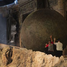 Two Disney Cast Members push a boulder up an Indiana Jones Adventure ramp.