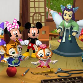 Goofy, Donald Duck, Daisy Duck, Minnie Mouse, and Mickey Mouse from Mickey Mouse Funhouse look at two little tigers standing at a table, with objects in front of them. One of the tigers is wearing a blue shirt and the other is wearing a pink and red dress with a flower in her hair. On the far right, an adult tiger is wearing a blue and red dress with a matching headdress; to her left a fairy wearing a gray and green dress with white wings.