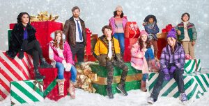 A promo image for Disney Branded Television&rsquo;s The Naughty Nine featuring Winslow Fegley as Andy, Camila Rodriguez as Dulce, Derek Theler as Bruno, Deric Mccabe as Jon Anthony, Clara Stack as Rose, Anthony Joo as Lewis, Ayden Elijah as Albert, Imogen Cohen as Ha-Yoon, and Madilyn Kellam as Laurel. The group is sitting on or standing near giant wrapped gifts, on a floor covered in snow. They&rsquo;re all wearing jackets; some wear hats, gloves, and scarves.