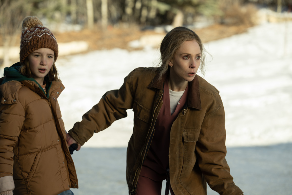In a scene from Fargo, Scotty Lyon, played by Sienna King, holds hands with Dorothy "Dot" Lyon/Nadine Tillman, played by Juno Temple, who crouches in front of her.