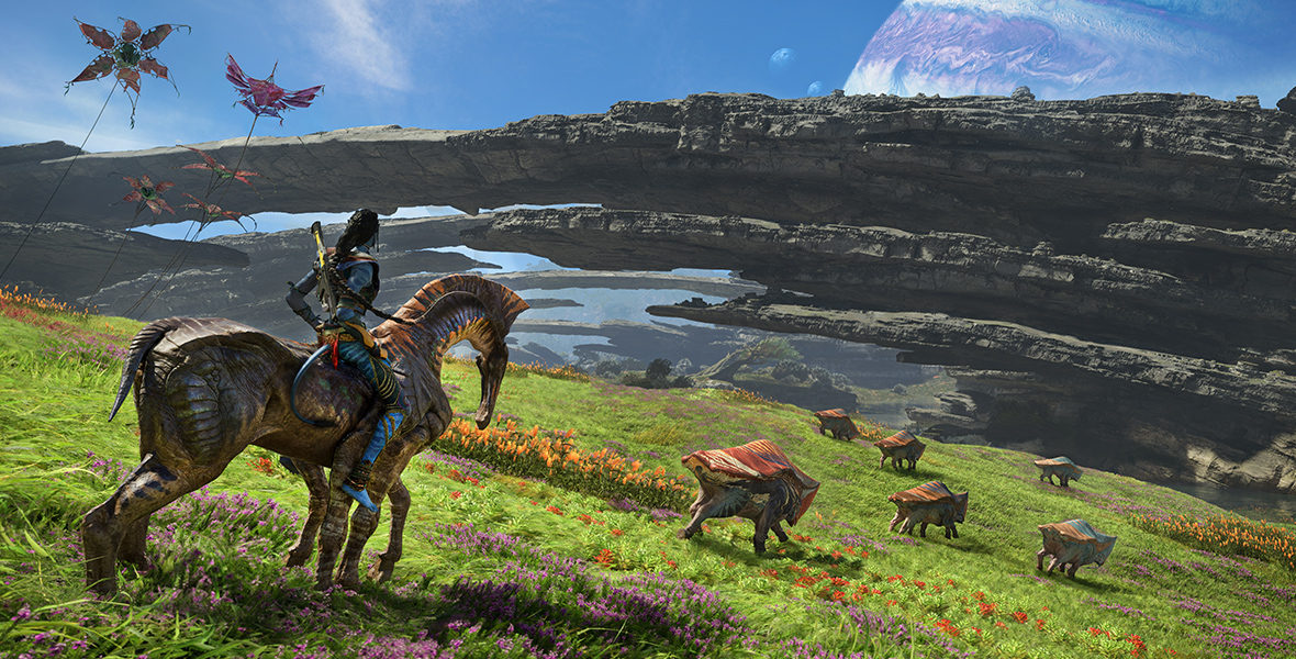 A Na’vi rides a creature in a rolling field, observing other alien creatures running toward bridge-like rock formations.