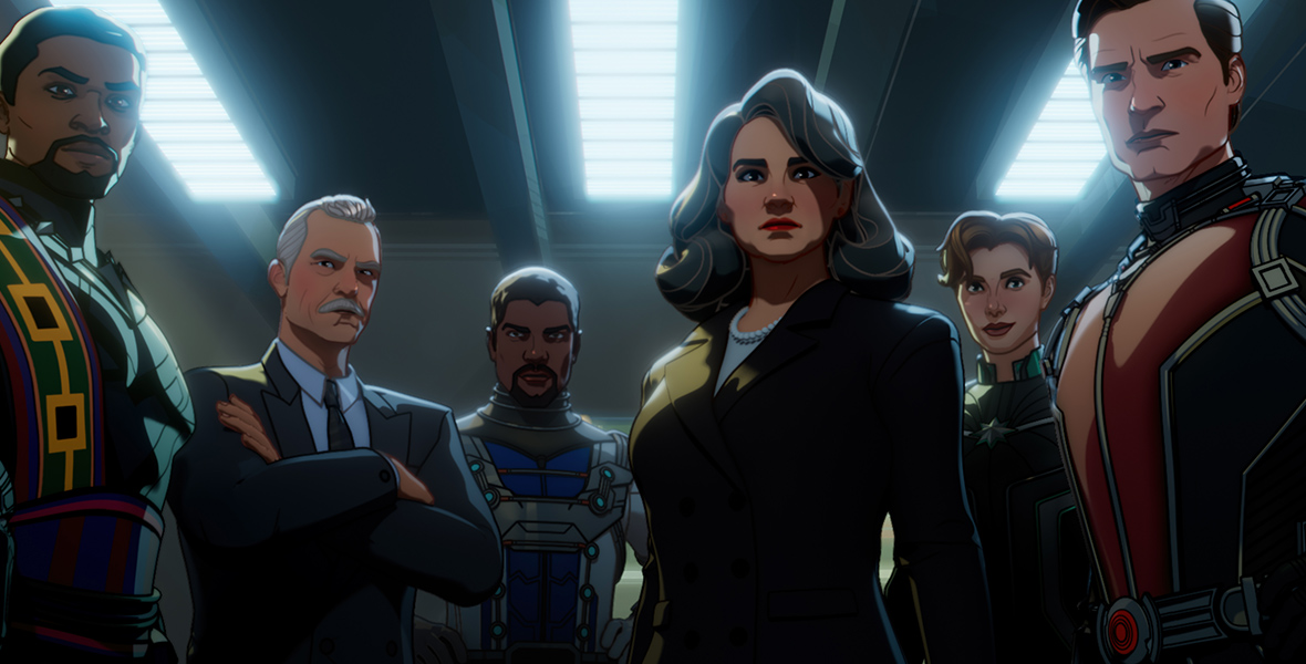 In an image from Marvel Studios’ What If? season 2, Black Panther/King T’Chaka, Howard Stark, Bill Foster/Goliath, Peggy Carter, Dr. Wendy Lawson/Mar-vell, and Hank Pym/Ant-Man are standing in a semi-circle in a darkened room, looking forward.