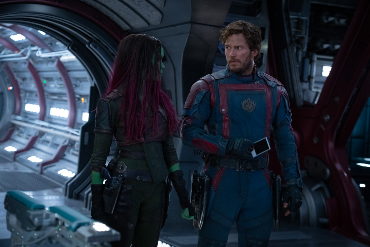 In a scene from Marvel Studios’ Guardians of the Galaxy Vol. 3, the green-skinned assassin Gamora, played by Zoe Saldaña, and the Celestial human Peter Quill, played by Chris Pratt, stare at each other as they walk inside a spaceship. Peter is holding a Polaroid photograph.