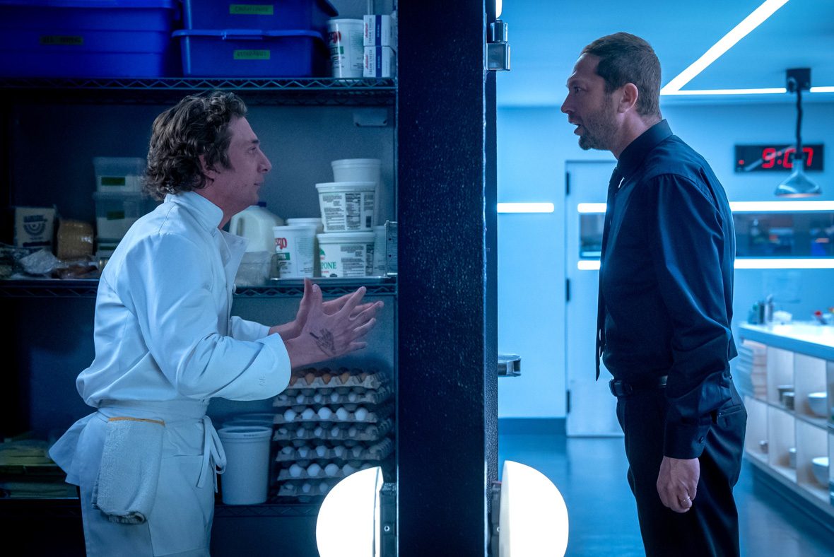 In a scene from The Bear, Carmen "Carmy" Berzatto, played by Jeremy Allen White, stands inside of a large refrigerator and shouts at Richard "Richie" Jerimovich, played by Ebon Moss-Bachrach, who stands on the other side of the door in the kitchen.