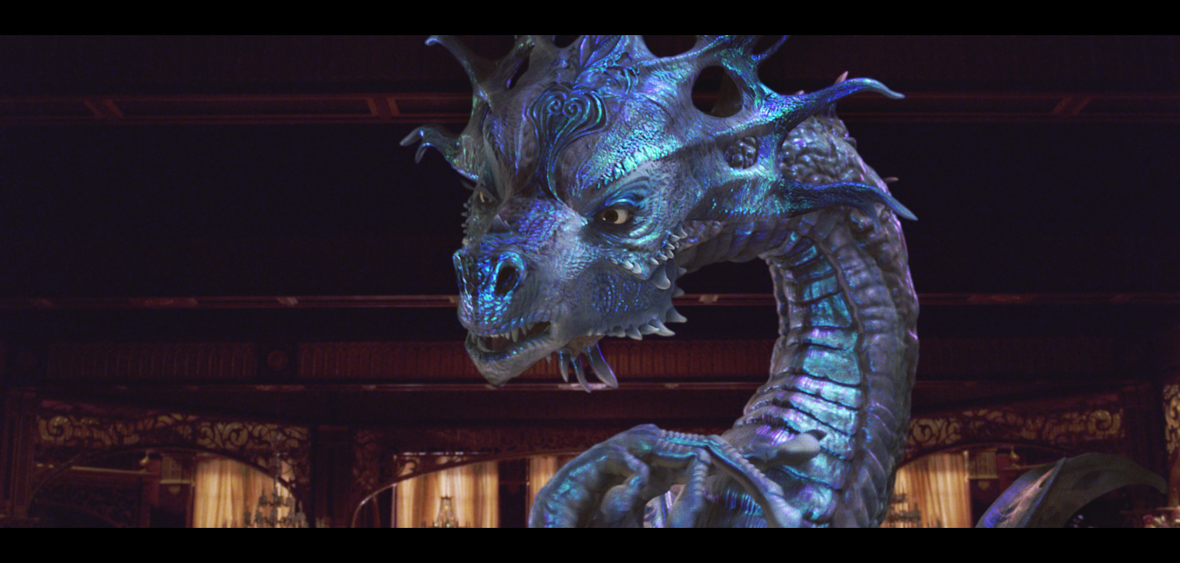 Dragon Narissa fills the screen in a close up shot. The background of the photo is the interior of a building, featuring a wooden ceiling and the top of five curtains.