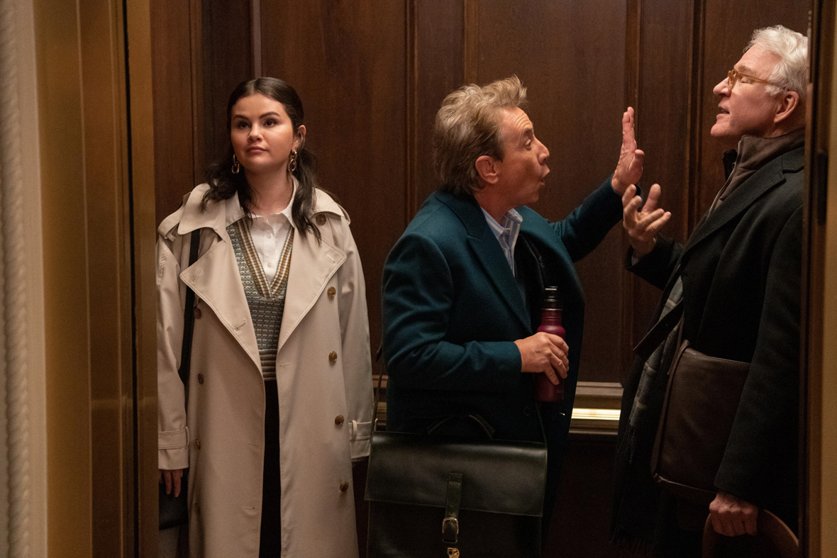 In a scene from Only Murders in the Building, Mabel Mora, played by Selena Gomez, stands inside an elevator as Oliver Putnam, played by Martin Short, and Charles-Haden Savage, played by Disney Legend Steve Martin, are engaged in a heated argument.