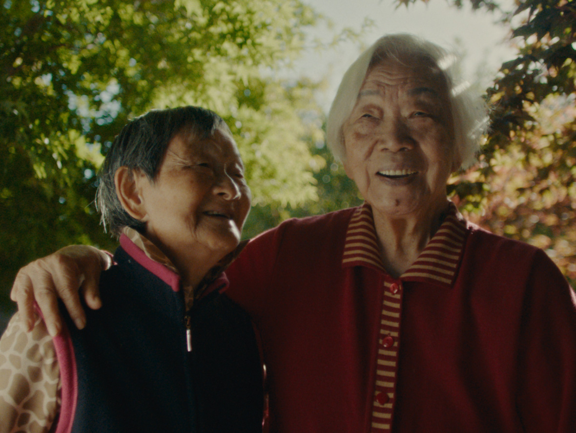 In a scene from Disney Branded Television's Nǎi Nai & Wài Pó, director Sean Wang's two grandmothers—Nǎi Nai and Wài Pó—embrace each other and share a laugh.