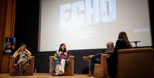 (From left to right) Chaske Spencer (Henry) and Alaqua Cox (Echo) take part in a panel presentation moderated by Joe Horse Capture, VP of Native Collections and Ahmanson Curator of Autry Museum of the American West and screening of Echo at the museum in Los Angeles on January 9, 2024. An ASL interpreter for both Cox and audience members sits at the far right. Both actors are draped in Native American tribal blankets.