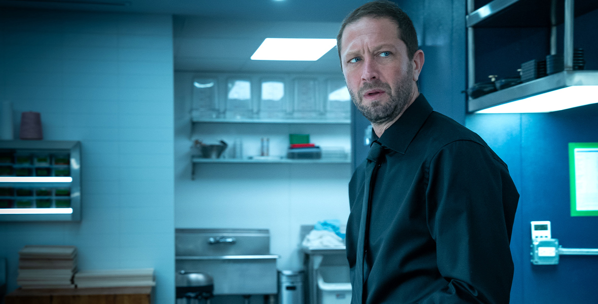 In a scene from The Bear, Richard "Richie" Jerimovich, played by Ebon Moss-Bachrach, wears an all-black ensemble. He is standing in the kitchen and appears stressed.