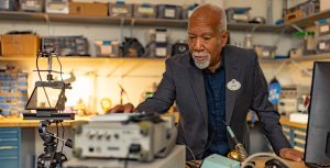 Imagineer Lanny Smoot wears a Disney nametag and tinkers in his workshop.