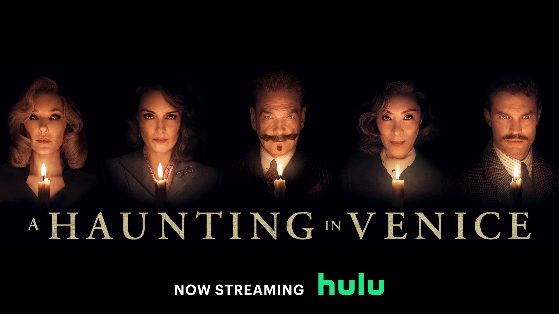 The characters of A Haunting in Venice stand in a row, all hidden by darkness except for their faces, which are illuminated by the orange glow of candles. Above their heads is the text “A Haunting in Venice, now streaming on Hulu.”