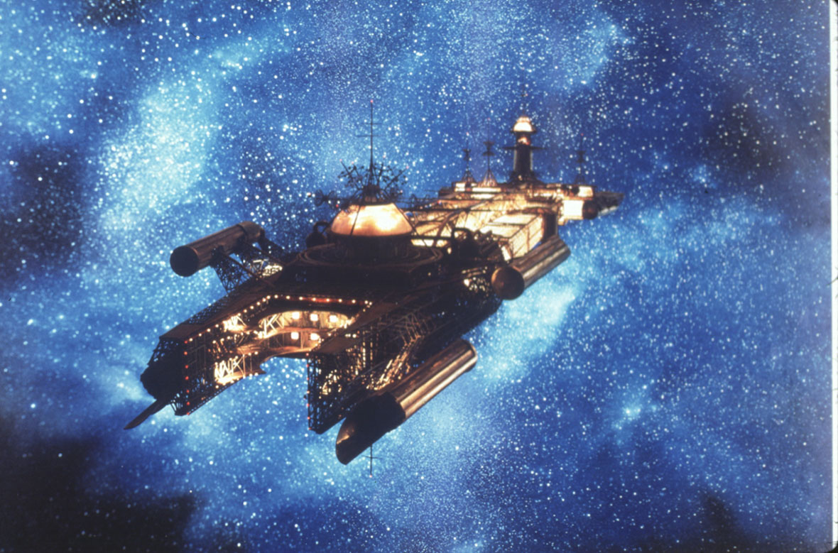 In an image from Disney’s The Black Hole, the USS Cygnus, a spaceship, floats through the blue and starry expanse of space.