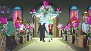 Aliens Korvo (left) and Terry (right) and are walking down a church isle. Korvo is wearing a dark gray cloak and a red bowtie, and Jesse is wearing gray bermuda shorts, a red short-sleeve top, and a black bowtie. The church is adorned with white roses and pink hearts. Other characters the &nbsp;show are sitting in the pews, looking at the two aliens.