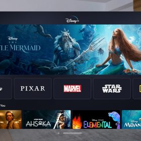 An iPad-like screen is floating in middle of a mid-century modern living room. The screen showcases the Disney+ app for Apple Vision Pro with The Little Mermaid as the showcase film in the center.