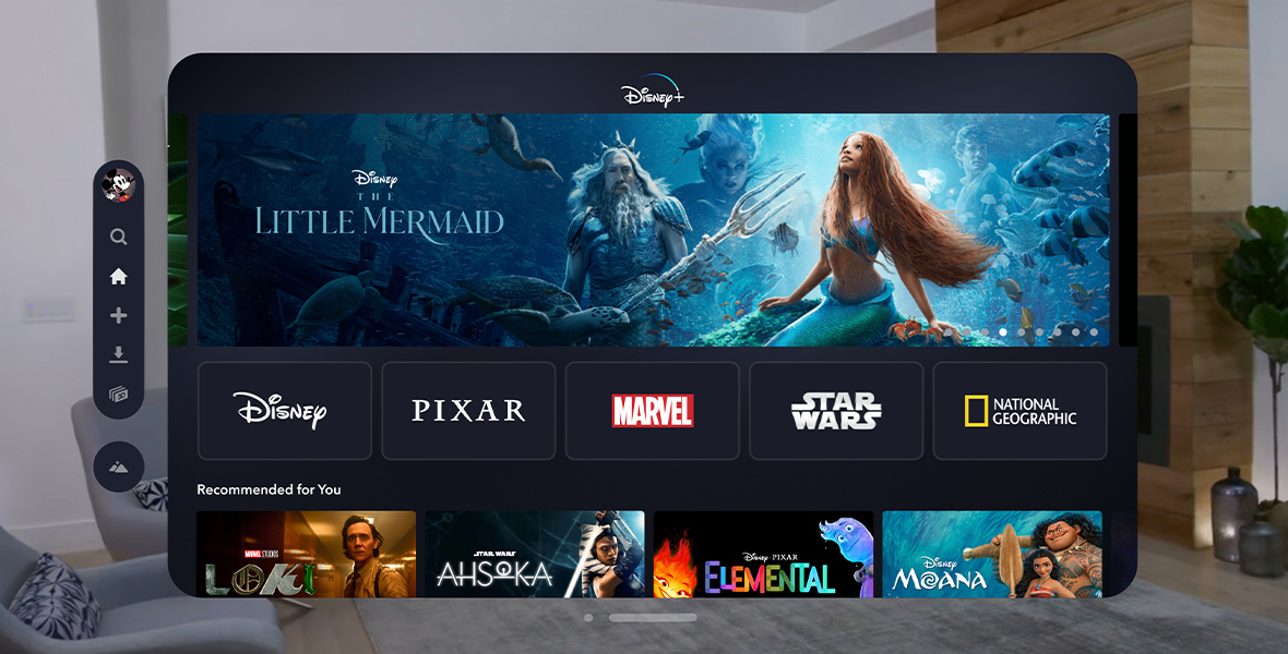 An iPad-like screen is floating in middle of a mid-century modern living room. The screen showcases the Disney+ app for Apple Vision Pro with The Little Mermaid as the showcase film in the center.