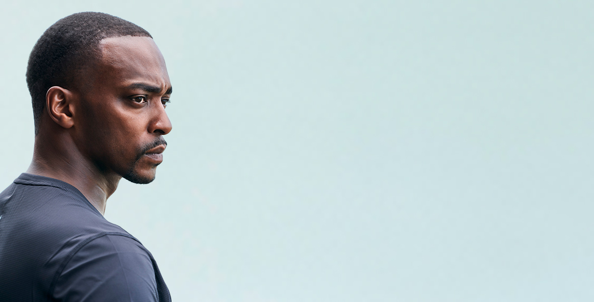 In a promotional image for Shark Beach, Anthony Mackie is seen in profile fishing for baby Bull Sharks in Lake Pontchartrain. He has a serious expression on his face and wears a navy high-tech-looking shirt.