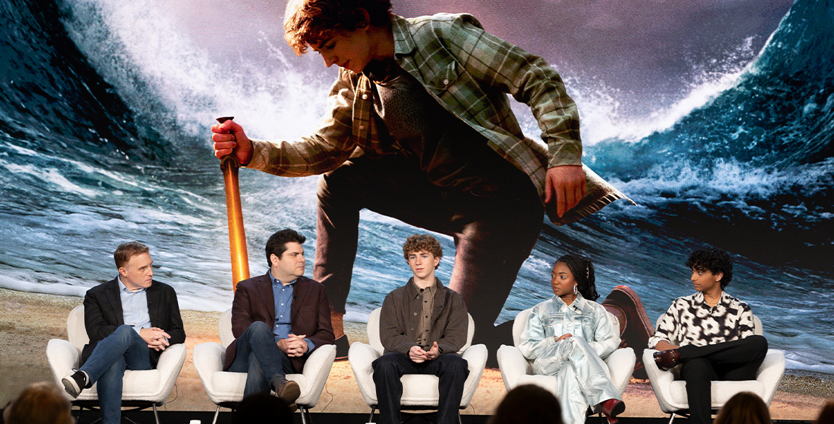 From left to right: Jonathan E. Steinberg, Dan Shotz, Walker Scobell, Leah Sava Jeffries, and Aryan Simhadri sit on a Percy Jackson and the Olympians panel during the Television Critics Association's Winter Press Tour. The series' key art is displayed onscreen behind them, which shows Scobell as Percy Jackson, wielding a sword and parting the sea.