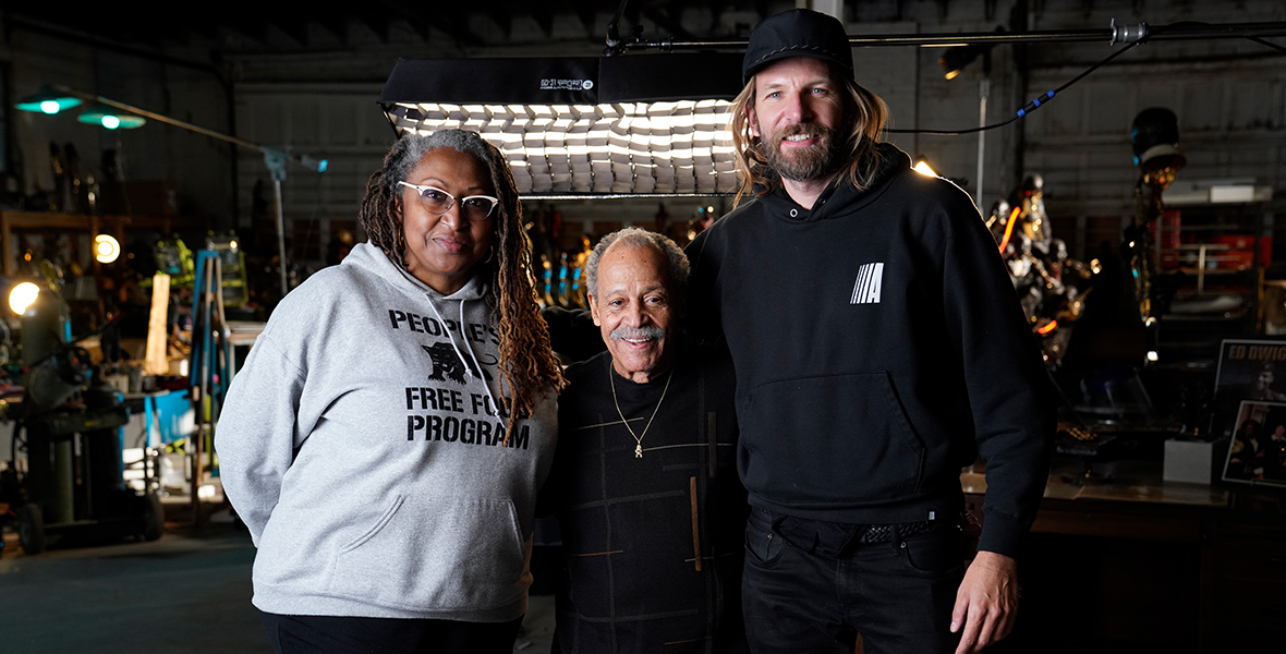 National Geographic Documentary Films’ The Space Race directors Lisa Cortés, left, and Diego Hurtado de Mendoza, right, pose with former test pilot Ed Dwight. Cortés is wearing a gray hoodie and black jeans; Dwight is wearing a black crewneck sweater and black pants; and Hurtado de Mendoza is wearing a black hat, a black hoodie, and black jeans.