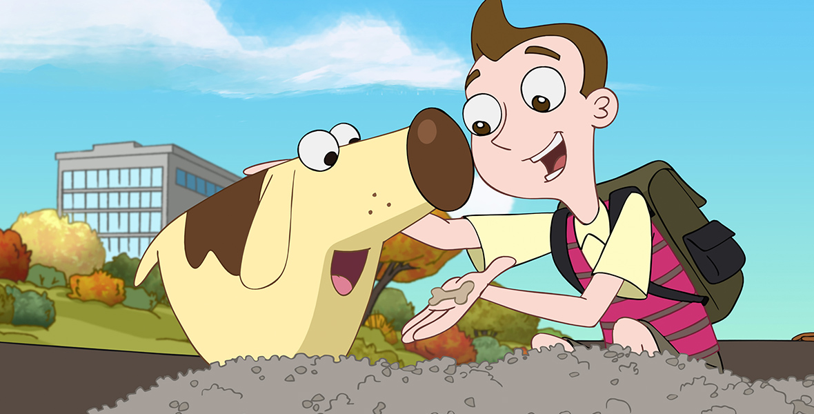 Milo from Milo Murphy’s Law crouches down to dog level to give Diogee a treat while patting his head. Milo is wearing a yellow polo shirt, a pink vest with brown stripes, and a brown backpack. Behind the two is a gray building with trees and shrubs.