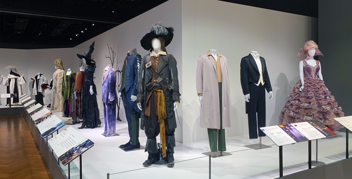 A display of numerous villain costumes on mannequins spreads out at an angle to the right and left in Heroes & Villains: The Art of the Disney Costume, as formerly presented at the Henry Ford Museum of American Innovation in 2022.