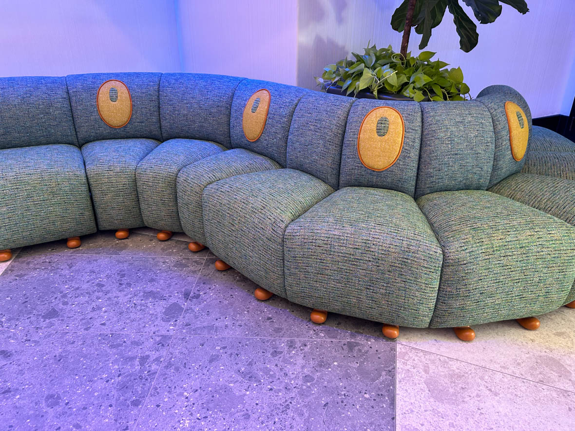 A green couch with yellow spots, stylized to look like the caterpillar Heimlich from A Bug’s Life. The couch has little brown feet running along the bottom of the cushions.