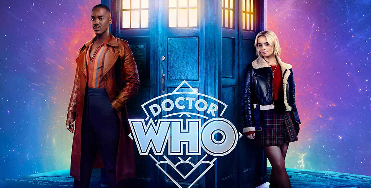 In a poster for the release of the Doctor Who series, Ncuti Gatway (left) and Millie Gibson (right) are leaning across a wooden telephone box. Gatwa wears a burgundy leather trench coat, gray sneakers with white accents, blue velvet pants, and a zipped-up knit top with colorful stripes. Gibson sports black combat boots, black sheer tights, a checkered mini skirt, a red top, and a shearling black leather jacket. From top to bottom reads: “BBC PRESENTS,” “COMIS JOYRIDE AWAITS,” “DOCTOR WHO,” “May 10,” and “Disney+.”