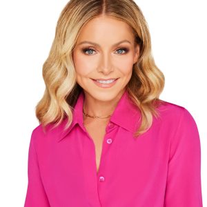 Disney Legend Kelly Ripa sports shoulder-length blonde hair, wearing a bright pink shirt, smiles at the camera with a white background.