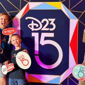 A family of D23 Members poses with photo props inspired by classic bowling in front of a gemstone facet patterned backdrop with a D23 15th Anniversary logo.