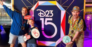 A family of D23 Members poses with photo props inspired by classic bowling in front of a gemstone facet patterned backdrop with a D23 15th Anniversary logo.