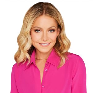 Disney Legend Kelly Ripa sports shoulder-length blonde hair, wearing a bright pink shirt, smiles at the camera with a white background.