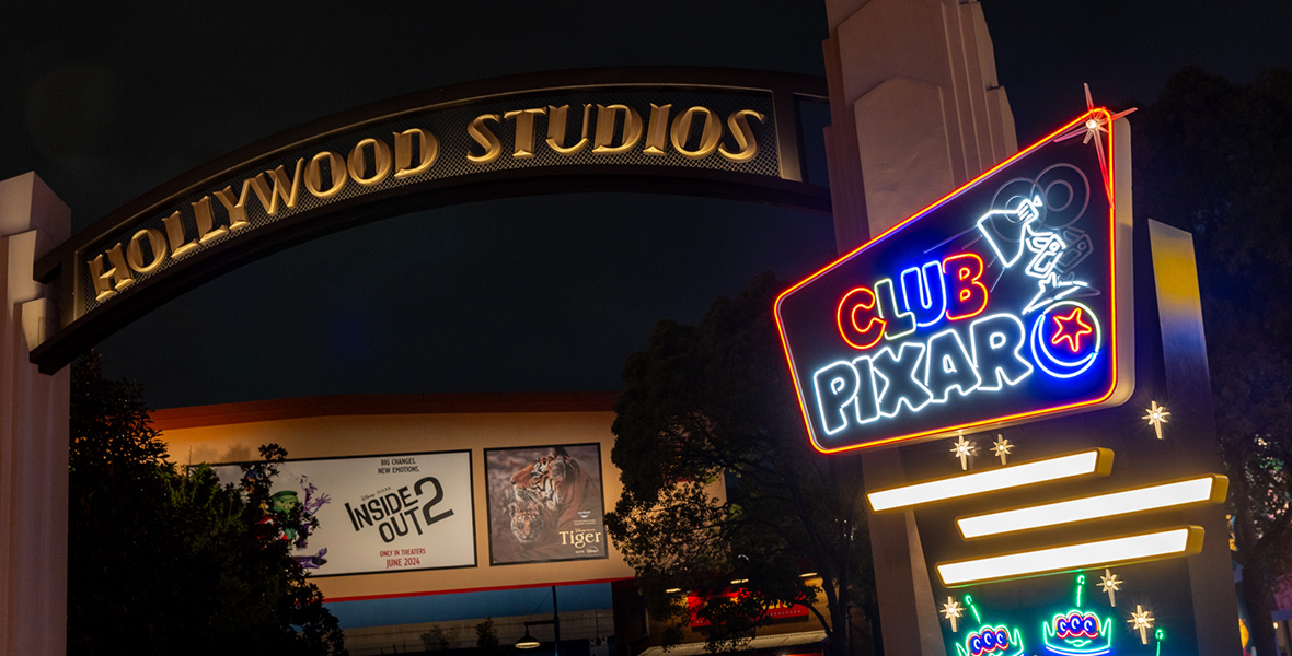 At Disney California Adventure Park, Hollywood Land transforms into Club Pixar for Pixar Fest. Beneath the “Hollywood Studios” arch, a neon sign reads “Club Pixar,” featuring the Pixar logo and the iconic Pixar lamp. Below the sign, a billboard showcases posters from Inside Out 2 and Disneynature's Tiger documentary.