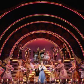 Photograph of the cast on stage performing the “Be Our Guest” musical number.