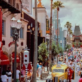 At Disney’s Hollywood Studios, Hollywood Boulevard is seen bustling with guests taking photos with a taxicab, shopping, and walking towards the Chinese Theatre.