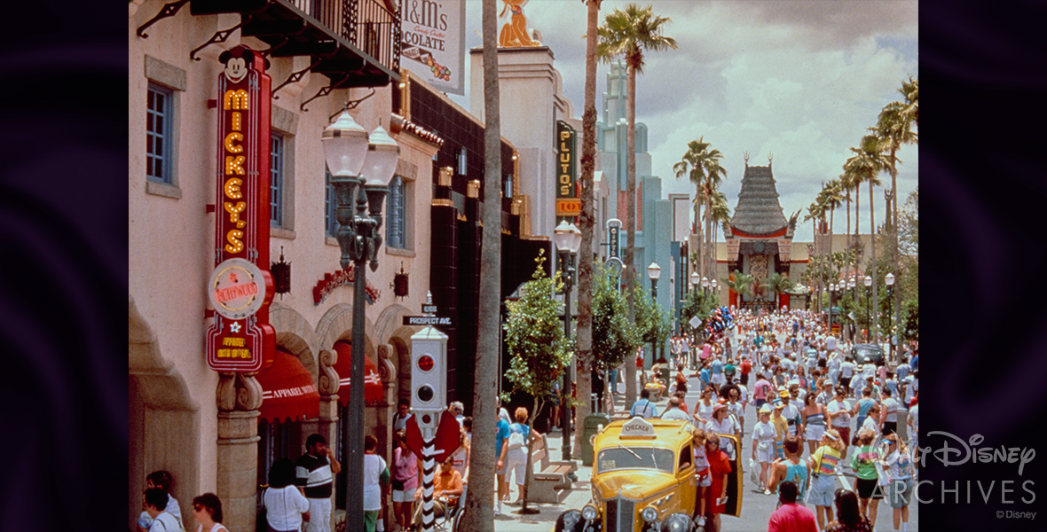 At Disney’s Hollywood Studios, Hollywood Boulevard is seen bustling with guests taking photos with a taxicab, shopping, and walking towards the Chinese Theatre.
