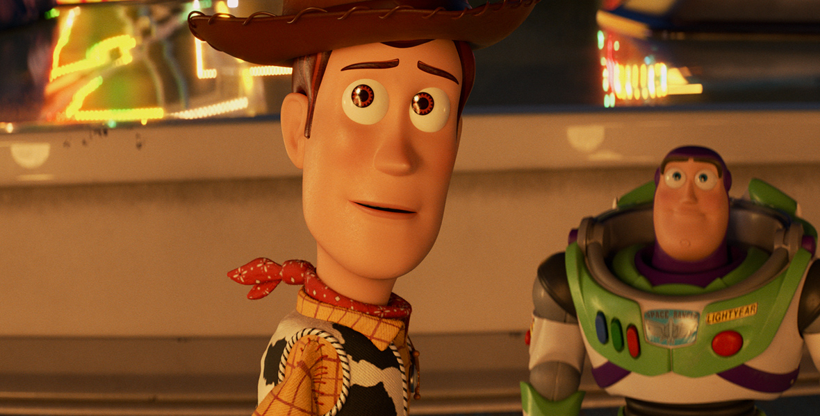 In a scene from Toy Story 4, Woody (left), a cowboy toy voiced by Tom Hanks, is looking ahead. He is wearing a brown cowboy hat, a yellow plaid shirt, a cow print vest, and a red neckerchief. On the right, Buzz Lightyear, a superhero toy action figure voiced by Tim Allen, is wearing a white and green space suit with purple accents, complete with retractable wings, and a red laser button on the chest. The background features neon lights and an elevated white surface with blue accents.