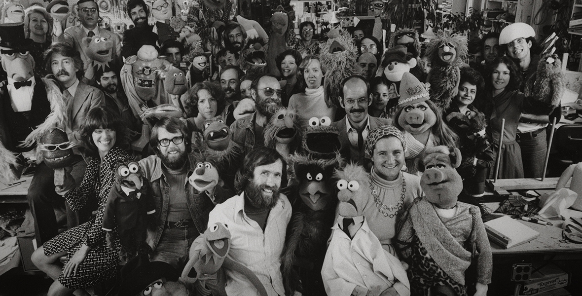 A black-and-white photo of Jim Henson and colleagues with Muppets.