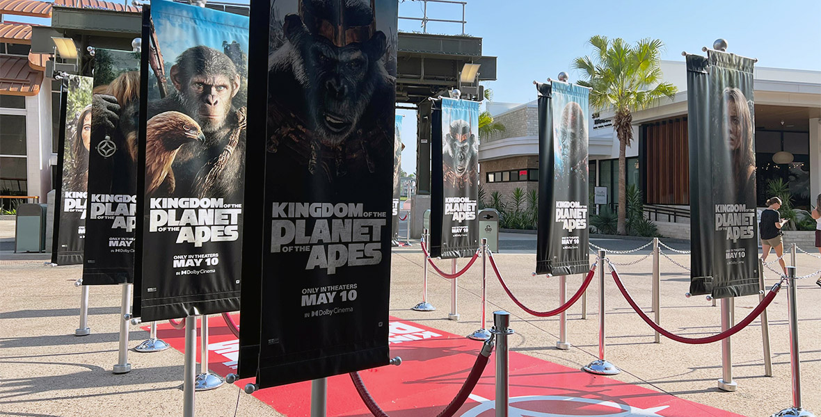 Banner Advertisements in front of AMC Disney Springs 24 Dine-In Theater, showcasing artwork and character posters from the film Kingdom of the Planet of the Apes.