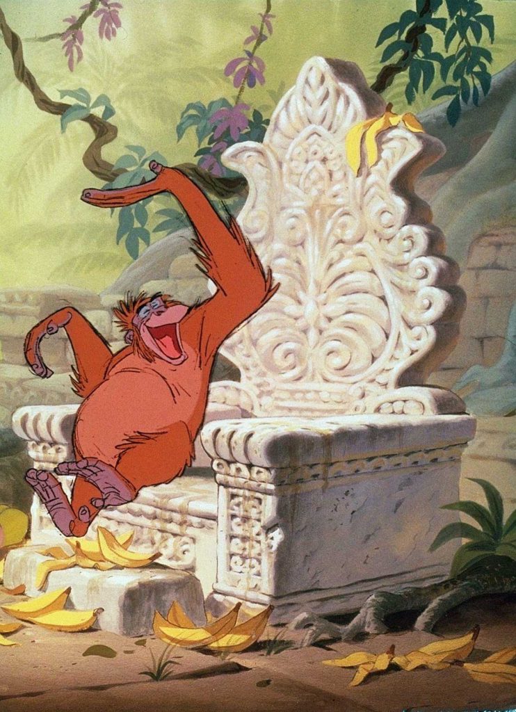 King Louie, from The Jungle Book, is sitting and laughing on a stone throne-like chair in the middle of the jungle with bananas, some already eaten, all around.